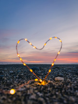 Heart symbol with bright fairy lights on the beach