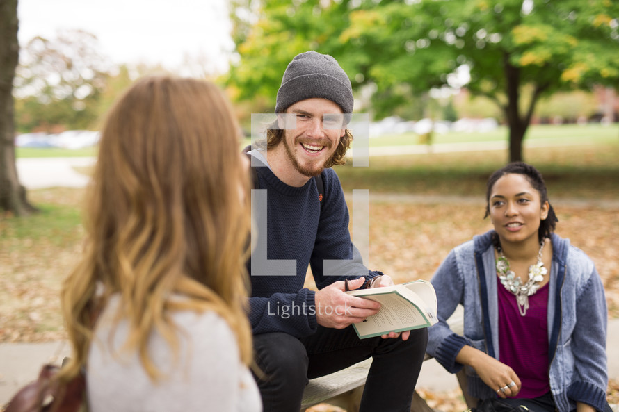 college students sitting on picnic tables on campus