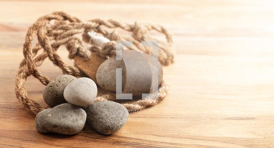 A Sling Shot and Stones on a Wooden Table from the Story of David and Goliath in the BIble 