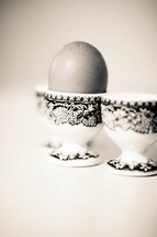 Brown, speckled Easter egg in vintage egg dishes.