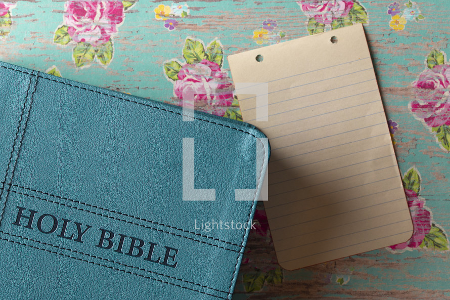 teal Bible and blank notebook paper 