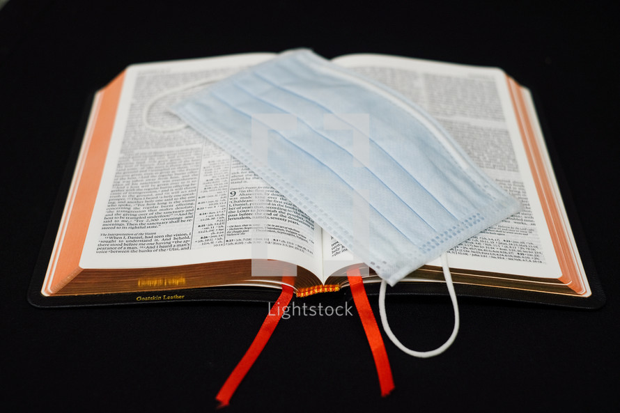 surgical mask on the pages of a Bible 