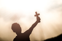 hand holding up a cross with sunlight at sunset in the background