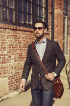 a man in a blazer carrying a satchel, walking to work 