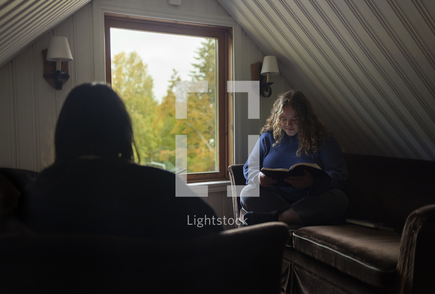 Two women reading her Bible in a quiet room with natural window light