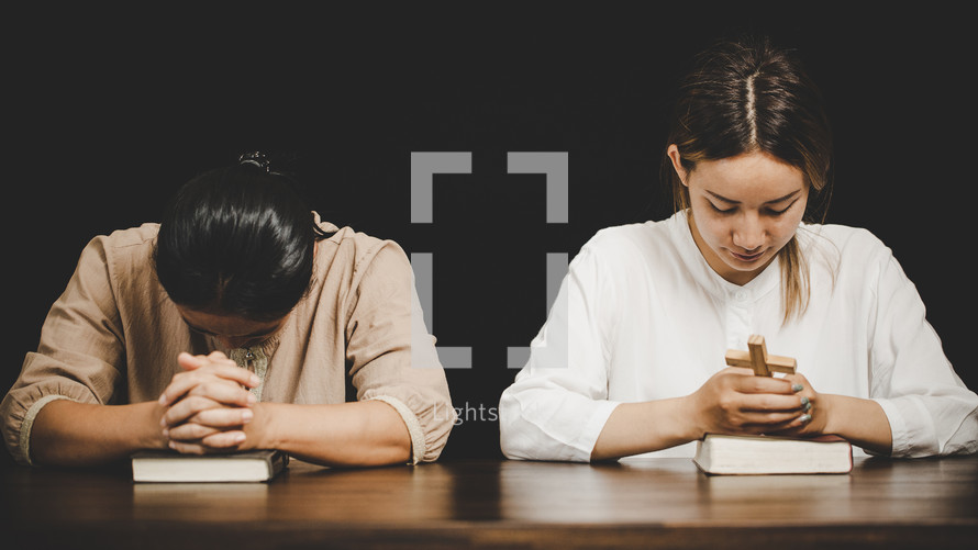 Two Asian women praying to God together.