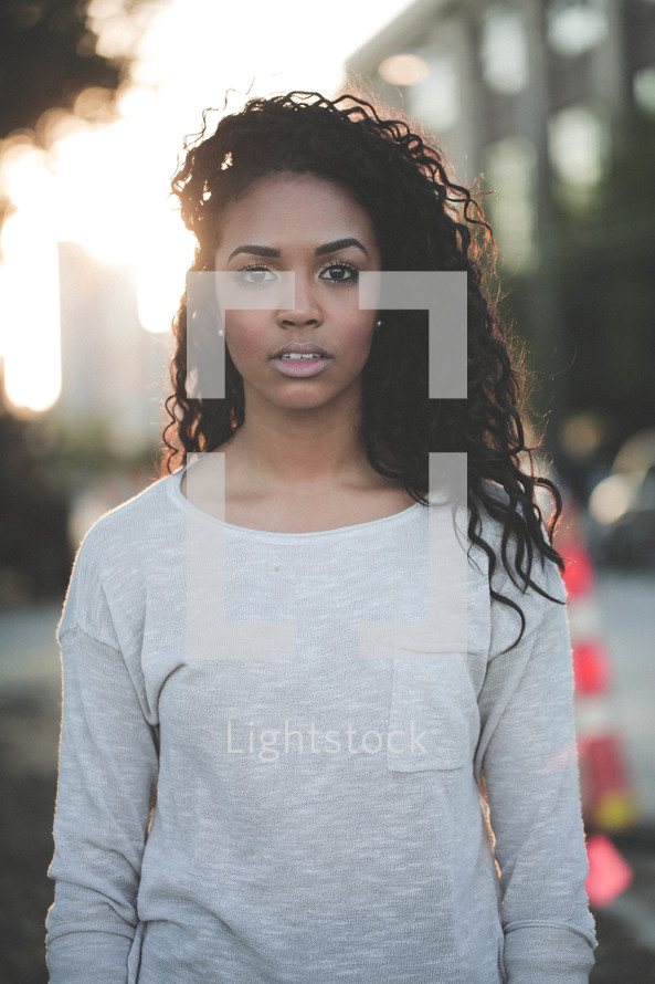 an angry young African-American woman outdoors under intense sunlight 