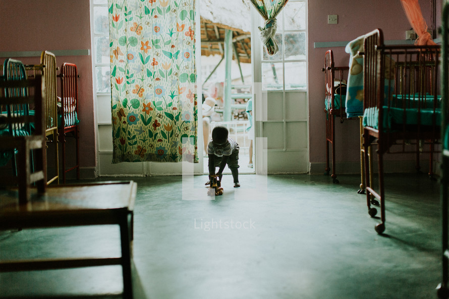 toddler boy playing with a toy truck in an orphanage room 