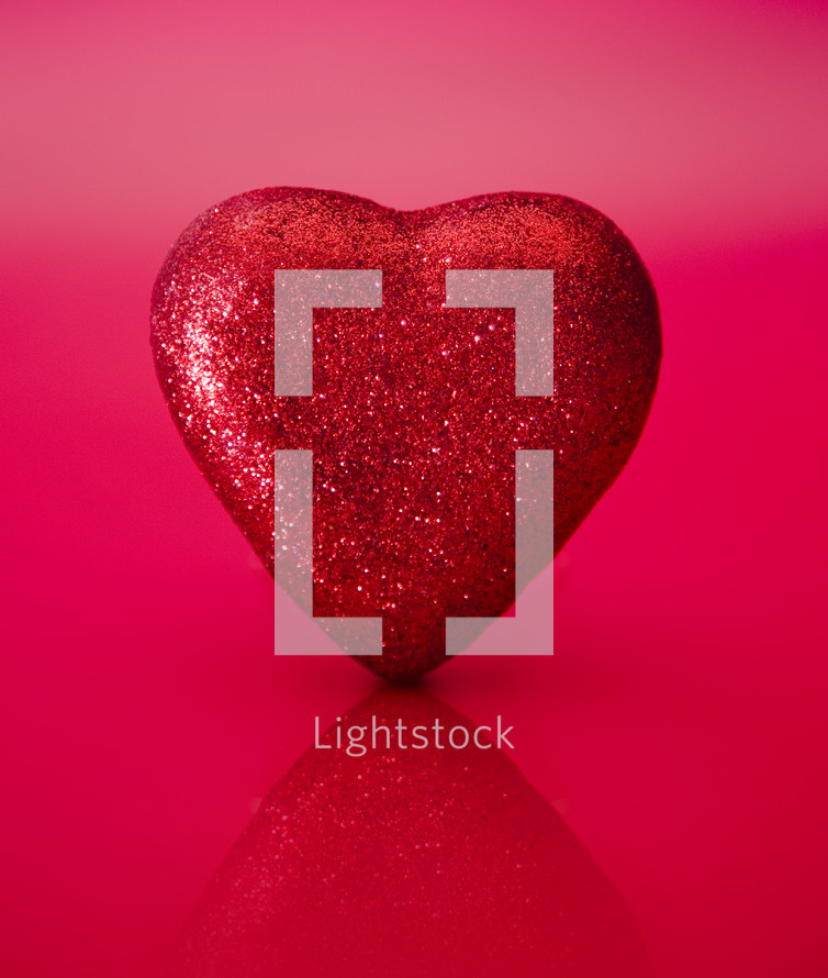 red glittery heart on a red and pink background 