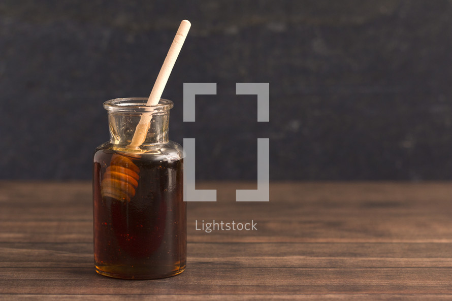 Honey with a Honeycomb Spoon on a Wood Background