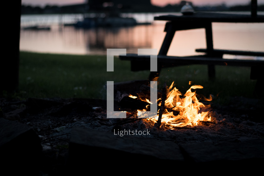 flames from a campfire by a lake 