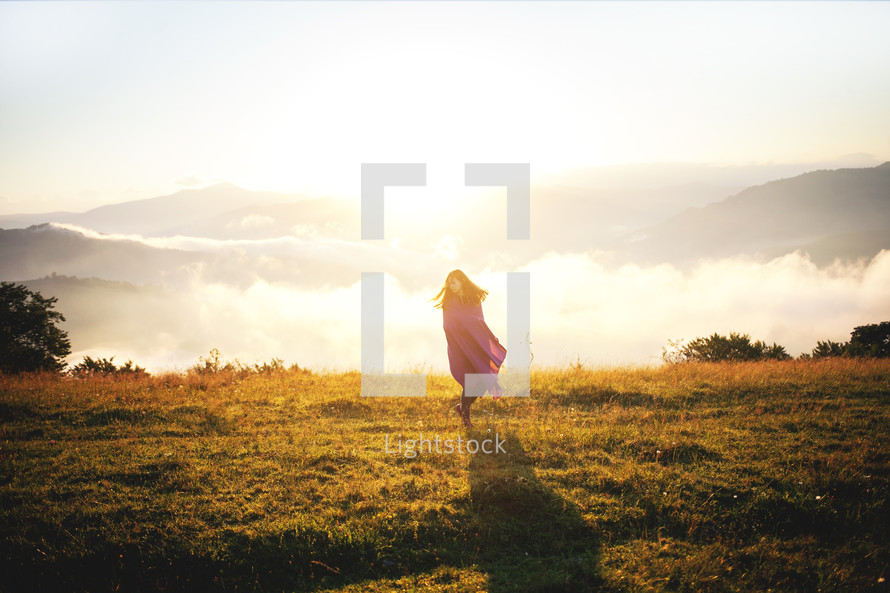teen girl wrapped in a blanket standing on a mountaintop 