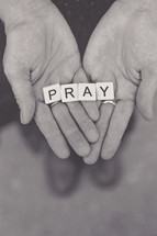 word pray in scrabbles pieces in a woman's hands 