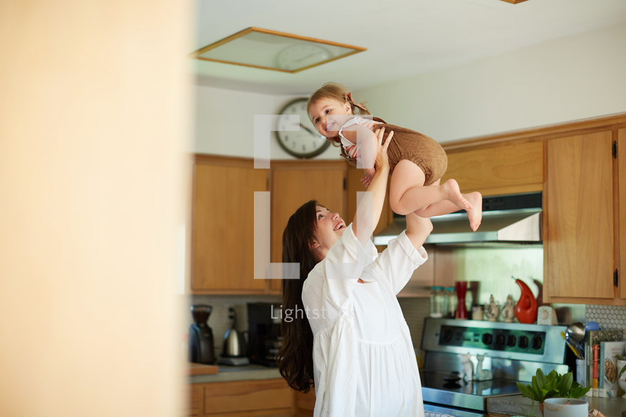 a mother holding her toddler daughter in the kitchen 
