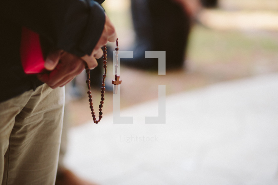 Catholic man holding rosary in prayer. 