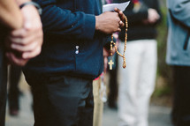 Young catholic man praying the rosary in a group outside