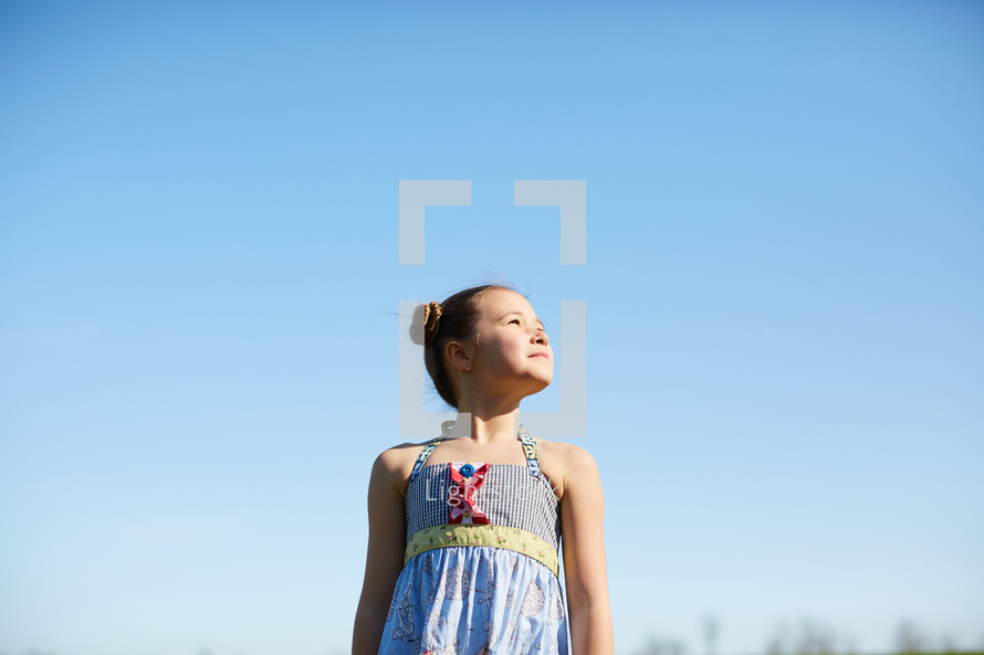 portrait of a girl standing against a blue sky 