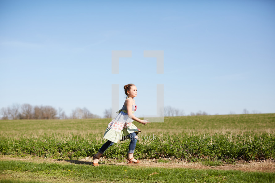a girl running in a field of grass