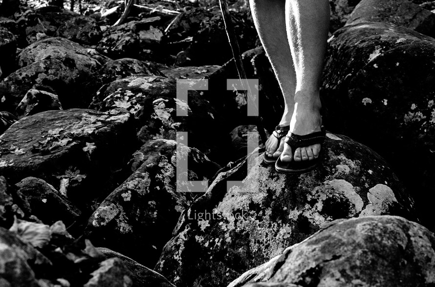 feet in flip flops standing on rocks 