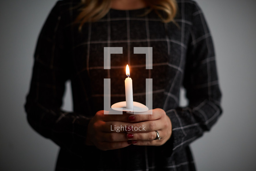 a woman holding a single candle 