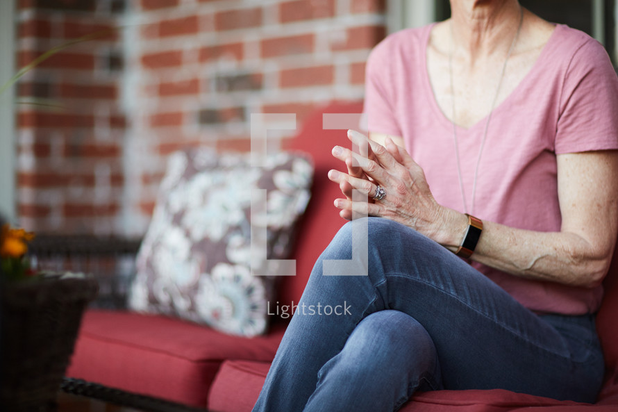 a woman sitting on a porch praying 