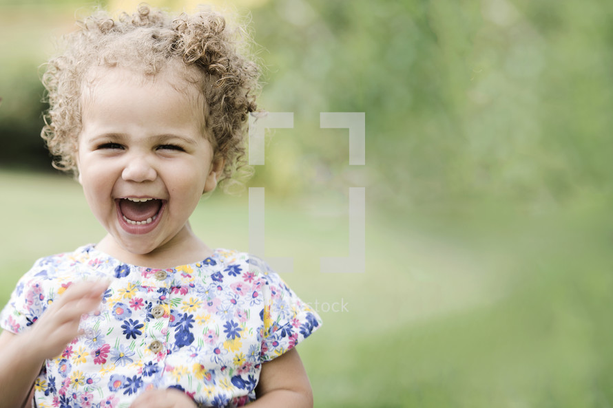 Biracial toddler girl laughing and playing outdoors. 