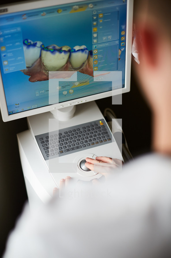 a dentist looking at computer scans of teeth 