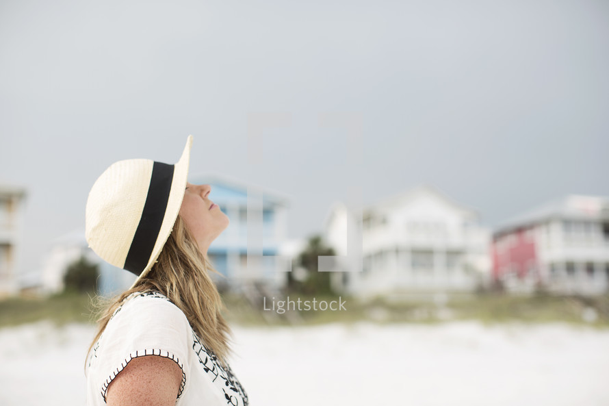 Woman standing outside on a beach looking up.