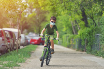 a boy riding a bike wearing a face mask 