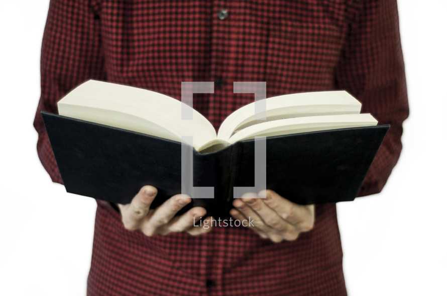 a man standing reading a Bible 