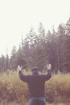 man standing outdoors with raised hands 