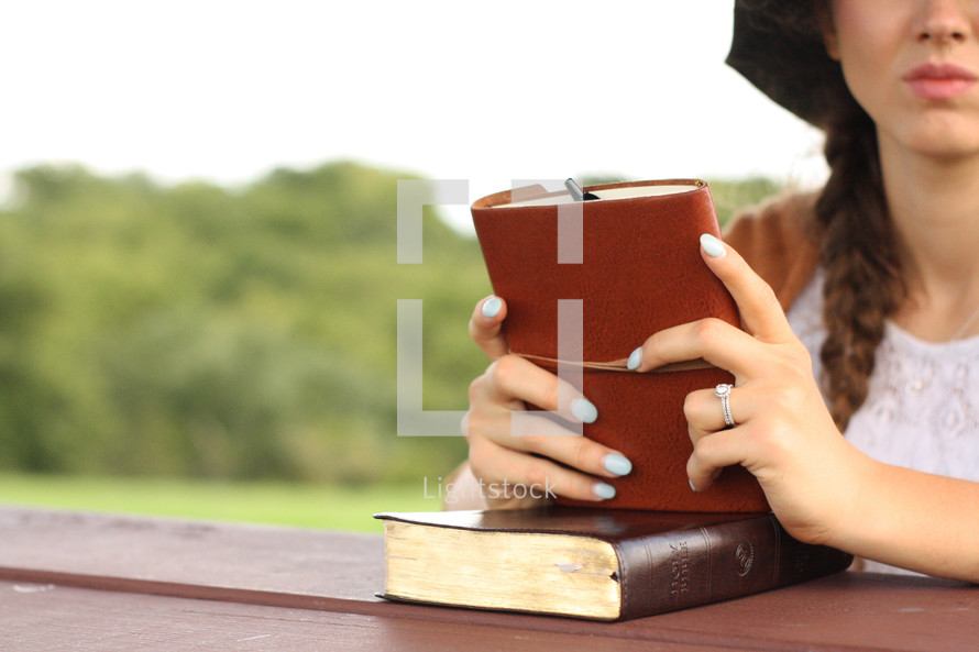 woman holding a Bible and leather journal 