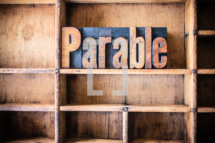 Wooden letters spelling "parable" on a wooden bookshelf.
