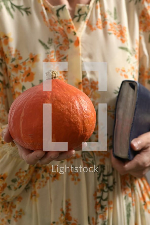 a woman holding a pumpkin and a Bible 