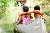 children in lifejackets in a canoe 