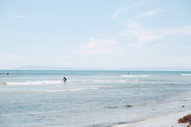 A surfer in shallow ocean water.