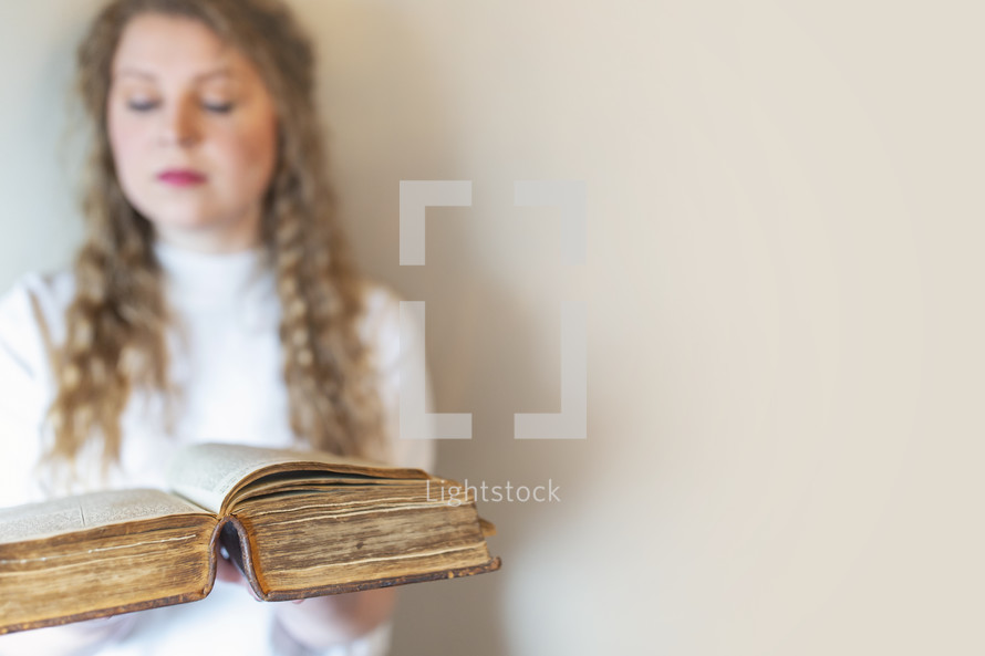 a young woman holding large leather Bible