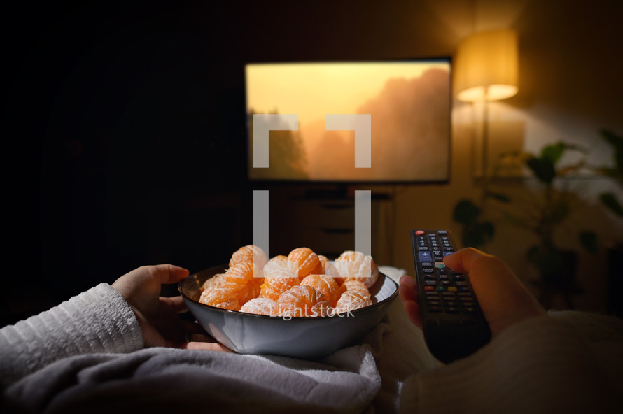 Relaxed Girl Watching Tv Holding Peeled Citrus Fruits and Remote Control 