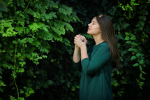 young woman standing outdoors praying 