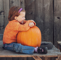 a child sitting with a pumpkin 