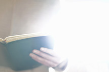 reading a Bible in glowing light 