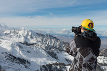 boy taking a picture of a snow capped mountain 
