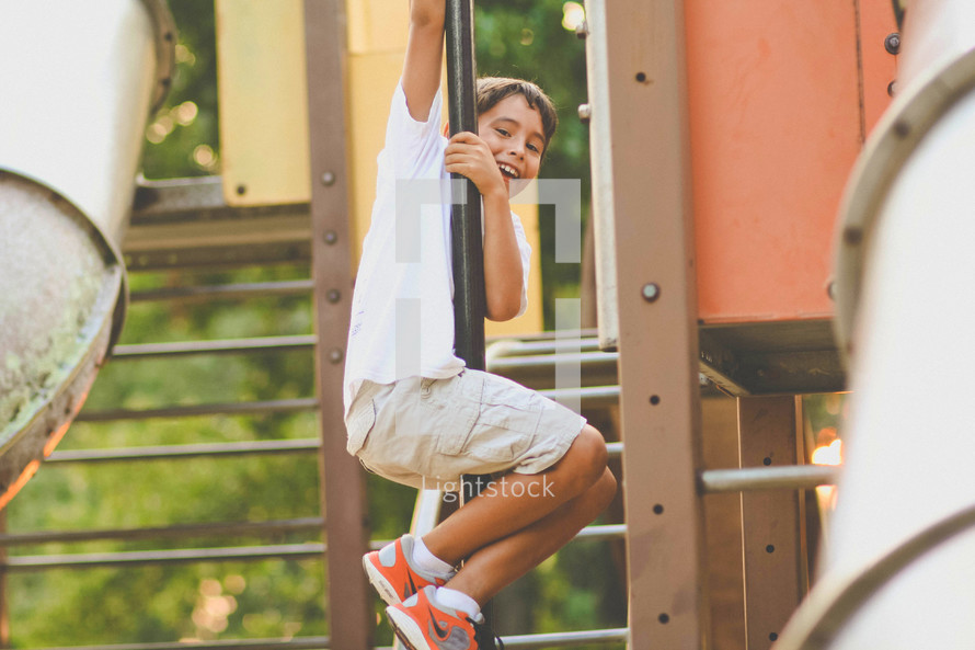child sliding down a pole at a playground 