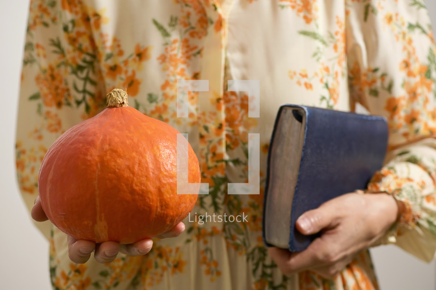 a woman holding a pumpkin and a Bible 