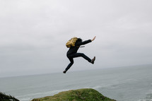 a man with a backpack leaping outdoors 