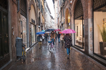 People walking on a cobblestone street in Greece in the rain 