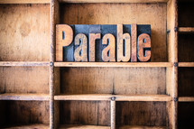 Wooden letters spelling "parable" on a wooden bookshelf.