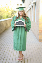 graduate holding a thanks mom and dad sign 