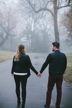 couple holding hands on a foggy path 