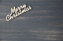 Merry Christmas wooden letters on a grey background.